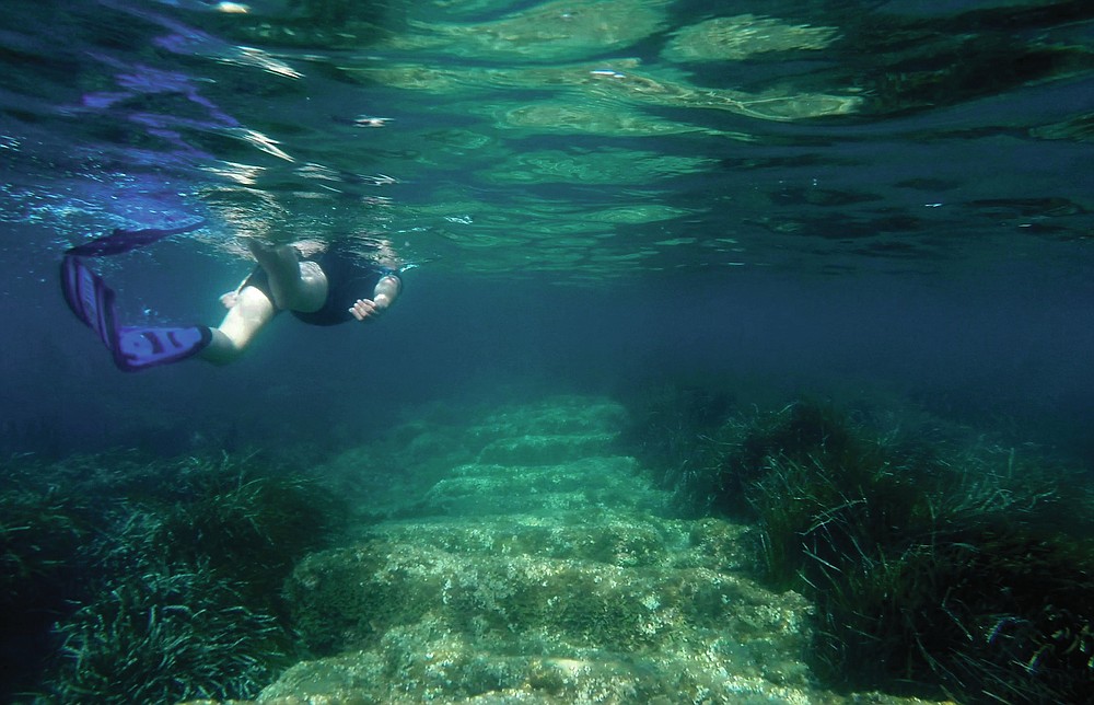 Cyprus Antiquities Department official Yiannis Violaris snorkels over submerged stone remains of the ancient harbor next of Amathus ancient city, in the eastern Mediterranean island of Cyprus, on Thursday, July 1, 2021. Lying just a few feet underwater a mere 200 feet off the coastline near the resort town of Limassol, this 2,400 year-old harbor said to be built Alexander the Great's successors will soon be Cyprus' newest tourist attraction where adventurous holidaymakers could snorkel over its submerged stone remains. (AP Photo/Petros Karadjias)