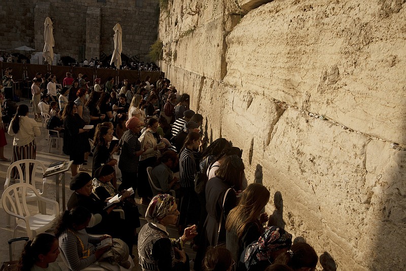 Worshippers pray in the women's section of the Western Wall, the holiest site where Jews can pray, in the shadow of the Mughrabi Bridge, a wooden pedestrian bridge connecting the wall to the Al Aqsa Mosque compound, in Jerusalem's Old City, Tuesday, July 20, 2021. The rickety bridge allowing access to Jerusalem's most sensitive holy site is at risk of collapse, according to experts. But the flashpoint shrine's delicate position at ground-zero of the Israeli-Palestinian conflict has prevented its repair for more than a decade. (AP Photo/Maya Alleruzzo)