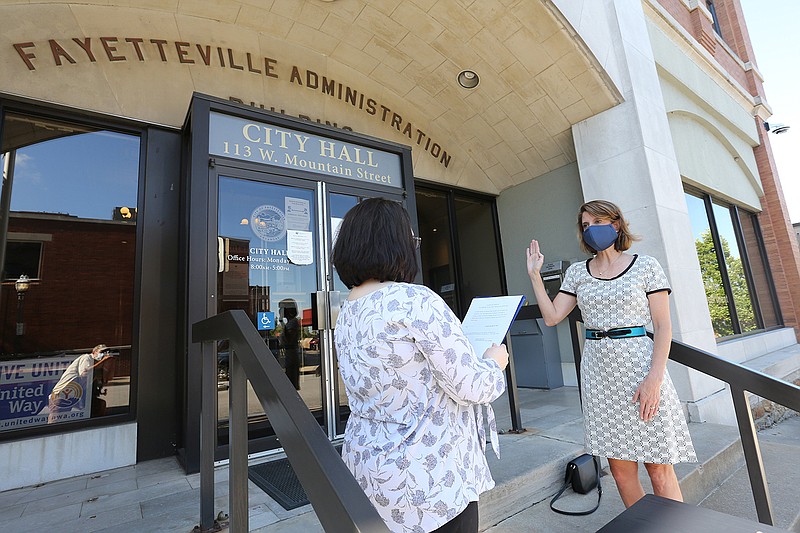 Kara Paxton (left), city clerk treasurer with the city of Fayetteville, administers the oath of office Friday, July 24, 2020, to Dr. Marti Sharkey as the city's public health officer on the steps of City Hall in Fayetteville. Sharkey, a pediatrician with a background in infectious diseases, will serve at the behest of the city's newly re-established board of health, which is advising administrators during the pandemic. Check out nwaonline.com/200725Daily/ and nwadg.com/photos for a photo gallery.
(NWA Democrat-Gazette/David Gottschalk)