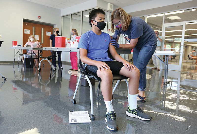 Patrick Jiang, an eighth grade student, receives the first shot of the Pfizer vaccine Friday, July 23, 2021, from Julie Ironside, a nurse with Nurses Crushing Covid, inside the Bulldog Lobby at Fayetteville High School. The Fayetteville Public Schools' free covid-19 vaccination clinic was held for ages 12 and up. A second dose clinic will be held Friday, August 13 at the school. Check out nwaonline.com/210724Daily/ and nwadg.com/photos for a photo gallery.(NWA Democrat-Gazette/David Gottschalk)
