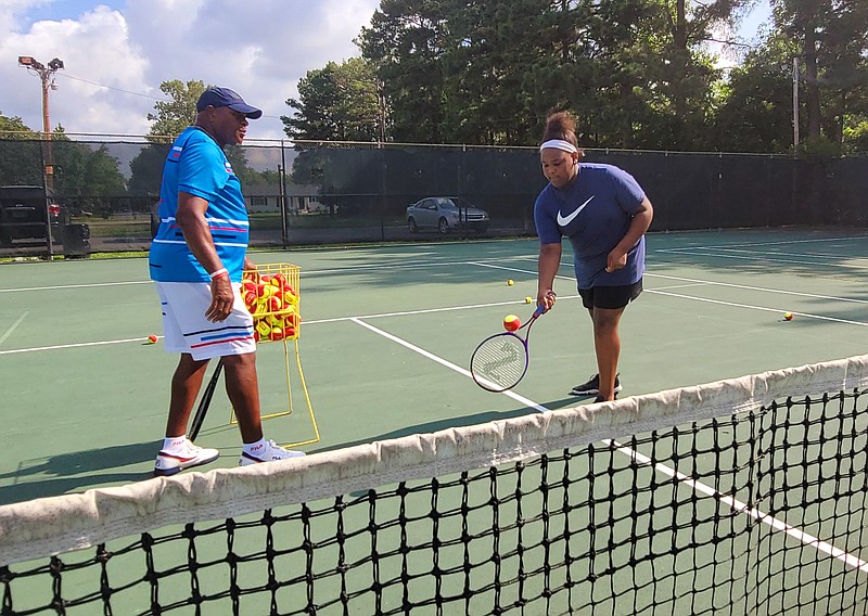 Nadia Miller, a 12-year-old White Hall Middle School student, is coached by Kreth Simmons as she hits the tennis ball over the net. (Pine Bluff Commercial/Eplunus Colvin)