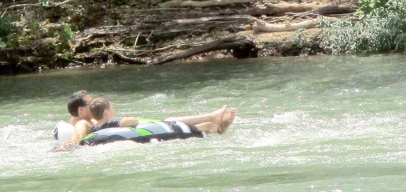 Marc Hayot/Herald-Leader A father and son float down the Illinois River on Friday at the Siloam Springs Kayak Park. About 10 people were at the kayak park cooling off during the summer heat.