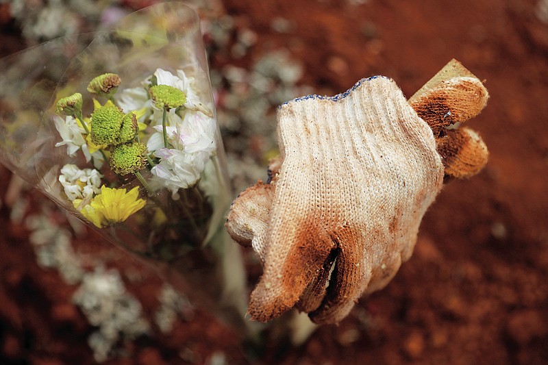 Used gloves belonging to a relative are left at the grave of a COVID-19 victim at a cemetery in Bogor, West Java, Indonesia on July 14, 2021. With the numbers of death increasing from the latest virus surge in Indonesia which has crippled the healthcare system in Java and Bali, relatives and residents decided to volunteer to dig graves using their own hoes and shovels to help exhausting gravediggers. (AP Photo/Achmad Ibrahim)