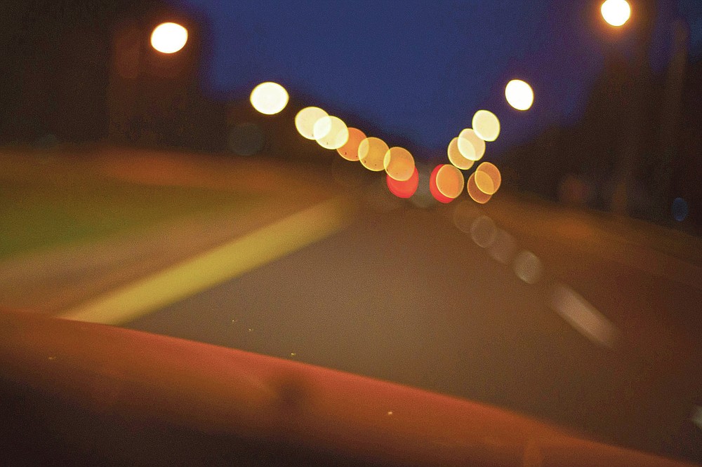 Lights from street signs and traveling cars drift out of focus in Paltaka, Fla., Thursday, April 15, 2021, along a road that runs from the former home of Charles Newcomb, the local KKK Exalted Cyclops, to where he and accomplices traveled to scope out the home of Warren Williams, a Black man whom they were planning on kidnapping and murdering. (AP Photo/David Goldman)
