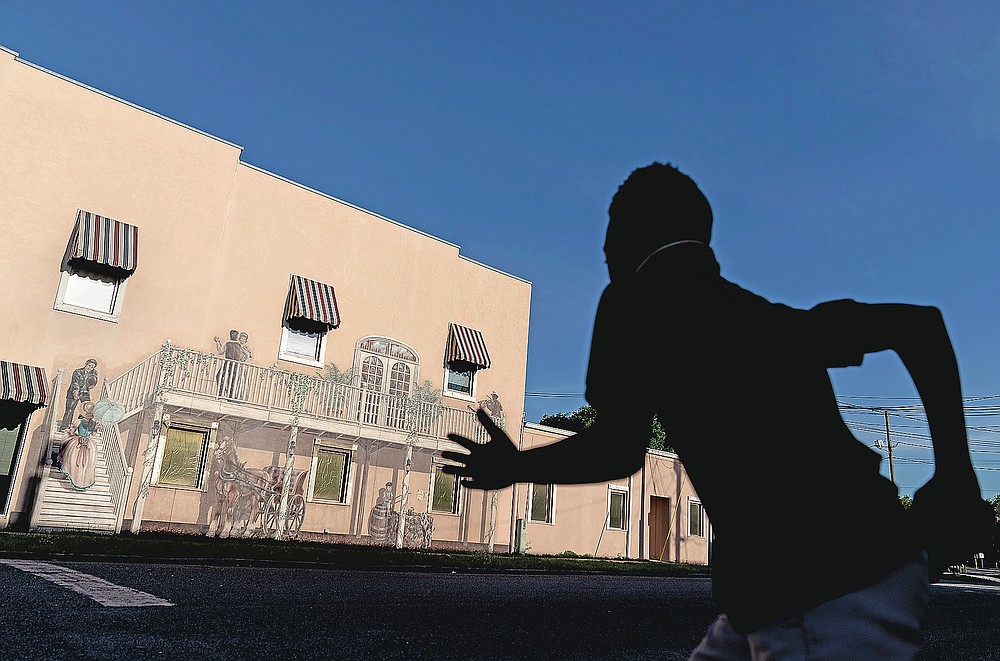 A mural titled "Bygone Days" decorates a downtown building as a child rushes to cross a street in Palatka, Fla., Tuesday, April 13, 2021. Jim Crow Florida was one of the most dangerous places in the South to be Black. In that era, a Black man in Florida was more at risk of being lynched - an execution without trial, often by gun or hanging - than in any other state, according to a University of Georgia study of lynching records. (AP Photo/David Goldman)