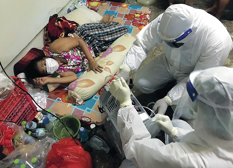 Volunteers from the "Saimai Will Survive" group in protective gear prepare oxygen for a struggling woman infected with COVID-19 on July 23, 2021, in Bangkok, Thailand. As Thailand's medical system struggles beneath a surge of coronavirus cases, ordinary people are helping to plug the gaps, risking their own health to bring care and supplies to often terrified, exhausted patients who've fallen through the cracks. (AP Photo/Tassanee Vejpongsa)