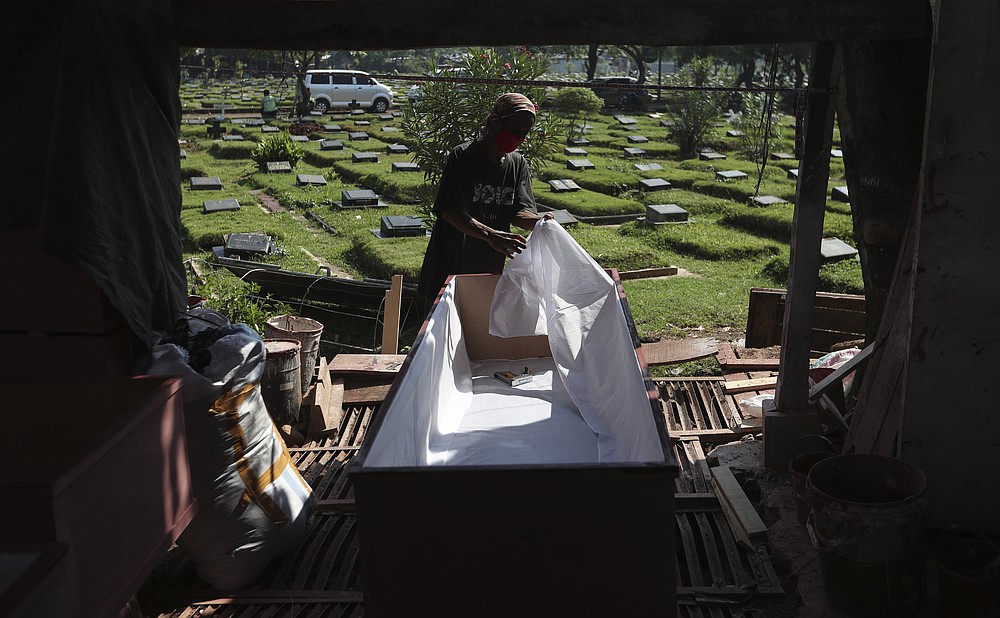 A worker makes a coffin to be used for victims of the coronavirus in Jakarta, Indonesia, Tuesday, July 27, 2021. Indonesia has been showing sharp increases since late June. (AP Photo/Achmad Ibrahim)