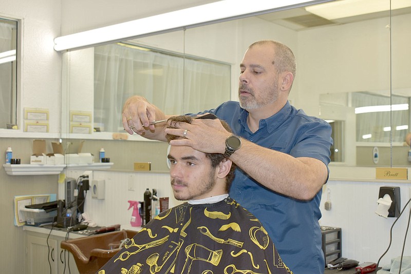 Rachel Dickerson/The Weekly Vista Mason Blaty of Bella Vista, seated, gets a haircut from Brett Smith of Town Center Barber Shop. The shop is going out of business July 31, but Smith and three other barbers are moving to a different shop.