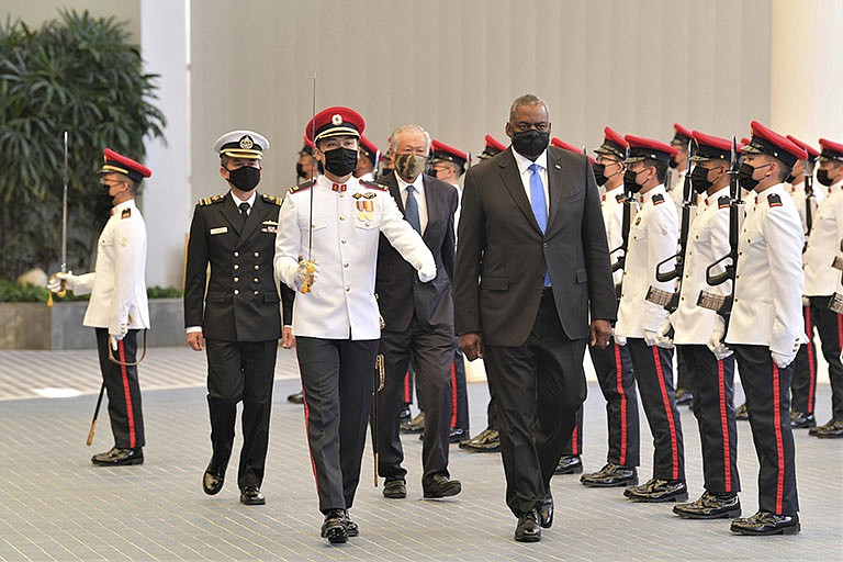 In this photo provided by the  Singapore Ministry of Defense, U.S. Defense Secretary Lloyd J. Austin along with Singapore Defense Minister Ng Eng Hen, back, review an honor guard at the Ministry of Defense Tuesday, July 27, 2021 in Singapore. Austin decried the actions of Myanmar's military rulers as unacceptable on Tuesday, while urging a regional bloc to keep demanding an end to violence. Austin also applauded the Association of Southeast Asian nations for its efforts on the issue, which included forging a consensus with Myanmar’s military leader in April. (Singapore Ministry of Defense via AP)