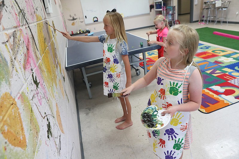 All Children’s Academy students Maeleigh Ritter, 8, Bennie Sharp, 6, and Ada Sharp, 10, right, paint a wall at the new All Children’s Academy Thursday. - Photo by Richard Rasmussen of The Sentinel-Record
