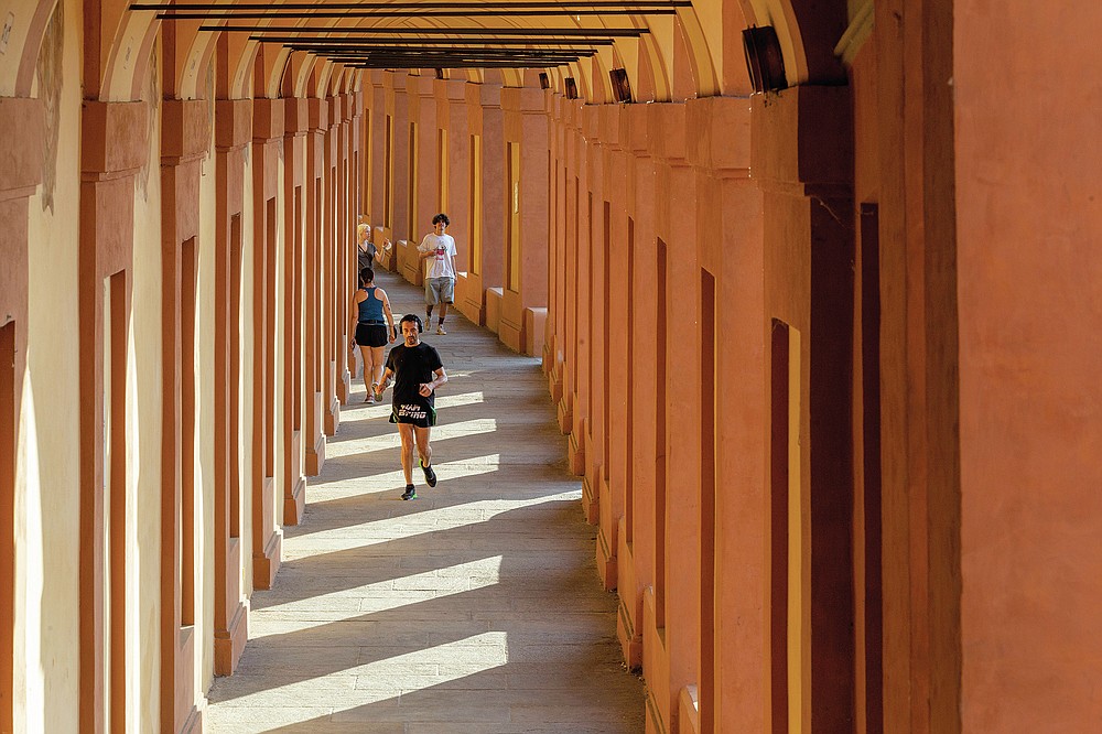 People walk along the porticoes in Bologna, Italy, Wednesday, July 28, 2021. Bologna's 12th-century porticoes, still part of the city's everyday life, have been added to the World Heritage List. At a meeting in China on Wednesday, the World Heritage Committee of UNESCO, the UN culture agency, inscribed the porticoes on the prestigious list. The addition raises to 58 the number of Italian sites on the list. (Guido Calamosca/LaPresse via AP)