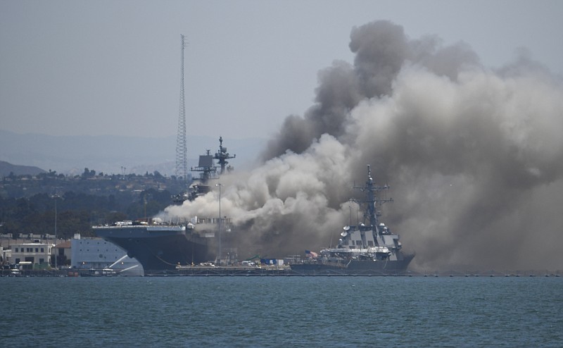 FILE - In this July 12, 2020, file photo, smoke rises from the USS Bonhomme Richard at Naval Base San Diego in San Diego after an explosion and fire. The U.S. Navy said Thursday, July 29, 2021, that charges have been filed against a sailor who is accused of starting a fire last year that destroyed a warship docked off San Diego. The amphibious assault ship called the USS Bonhomme Richard burned for more than four days and was the Navy's worst U.S. warship fire outside of combat in recent memory. (AP Photo/Denis Poroy, File)