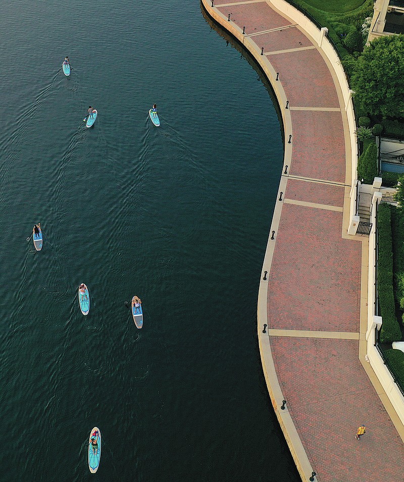 Paddleboarders with stand-up paddleboard company B'More SUP paddle alongside the promenade during a tour of Baltimore's Inner Harbor, Wednesday morning, July 21, 2021. (Jerry Jackson/The Baltimore Sun via AP)