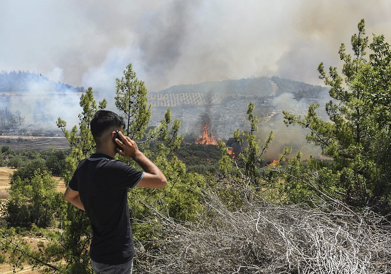 A man watches wildfires in Kacarlar village near the Mediterranean coastal town of Manavgat, Antalya, Turkey, Saturday, July 31, 2021. The death toll from wildfires raging in Turkey's Mediterranean towns rose to six Saturday after two forest workers were killed, the country's health minister said. Fires across Turkey since Wednesday burned down forests, encroaching on villages and tourist destinations and forcing people to evacuate. (AP Photo)