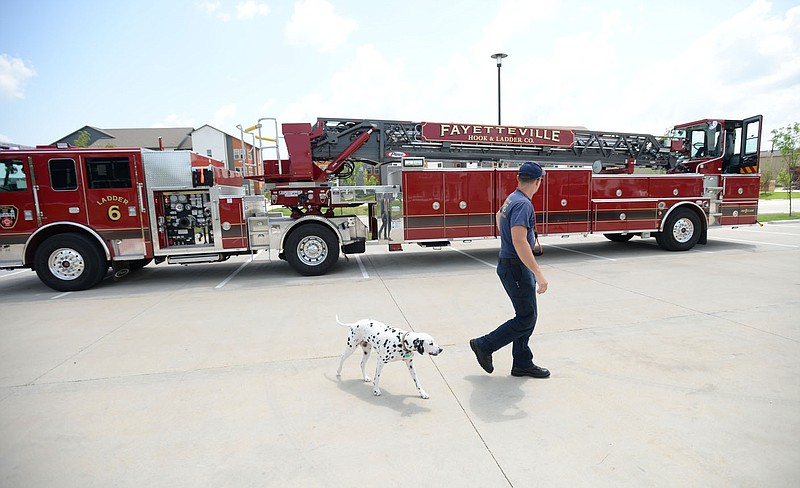 Martin Striefler, a firefighter with the Fayetteville Fire Department, and his dog, Ember, walk Tuesday, July 27, 2021, around Ladder 6 while training on the department's new tiller truck off Hollywood Avenue. The department bought its first tiller truck for $1.4 million using money from its share of city sales tax revenue. Early voting starts Tuesday, and Election Day is Aug. 10, to continue the 1-cent tax for operations and some capital expenditures. Visit nwaonline.com/210728Daily/ for today's photo gallery.
(NWA Democrat-Gazette/Andy Shupe)