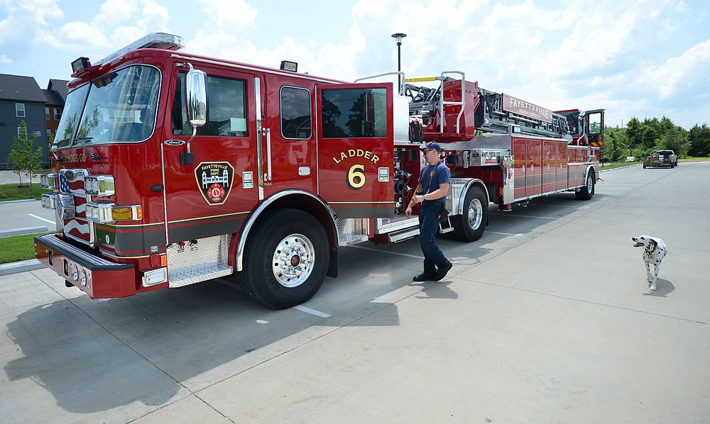 Martin Striefler, a firefighter with the Fayetteville Fire Department, and his dog, Ember, walk Tuesday, July 27, 2021, back to the cab of the Ladder 6 while training on the department's new tiller truck off Hollywood Avenue. The department bought its first tiller truck for $1.4 million using money from its share of city sales tax revenue. Early voting starts Tuesday, and Election Day is Aug. 10, to continue the 1-cent tax for operations and some capital expenditures. Visit nwaonline.com/210728Daily/ for today's photo gallery.
(NWA Democrat-Gazette/Andy Shupe)
