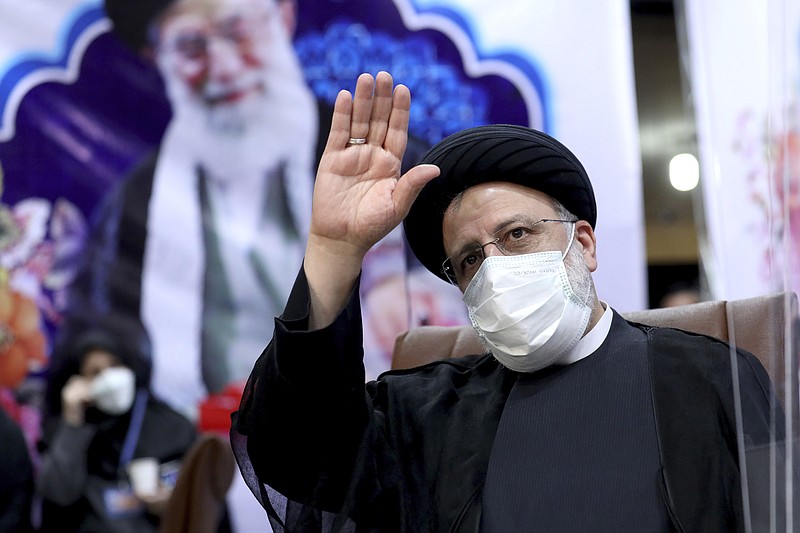 FILE - In this May 15, 2021 file photo, Ebrahim Raisi, then head of Iran's judiciary, waves to journalists while registering his candidacy for the upcoming presidential elections, in Tehran, Iran. Once President-elect Raisi, a protégé of Iran's Supreme Leader Ayatollah Ali Khamenei, shown in background, is sworn in as president this week, hard-liners will control all parts of the Islamic Republic's civilian government. Iran's inauguration of Raisi on Thursday represents the last stop in a slow slide from the hopes that the 2015 nuclear deal would open the Islamic Republic to the West. (AP Photo/Ebrahim Noroozi, File)