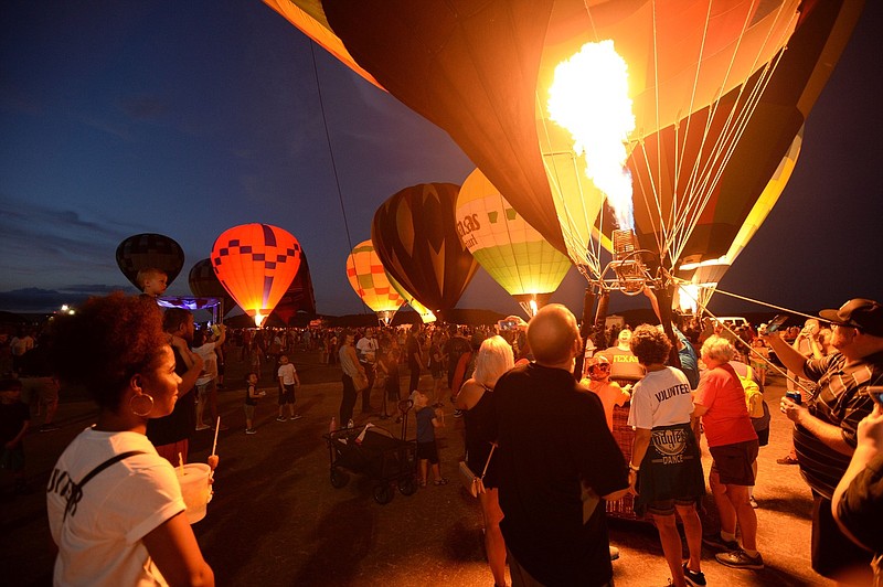 NWA Democrat-Gazette/ANDY SHUPE
Visitors watch Saturday, Aug. 24, 2019, as hot air balloons glow during the inaugural Soar NWA at Drake Field in Fayetteville. The event features hot air balloons, helicopter rides, live music, food and vendors to benefit Open Avenues.