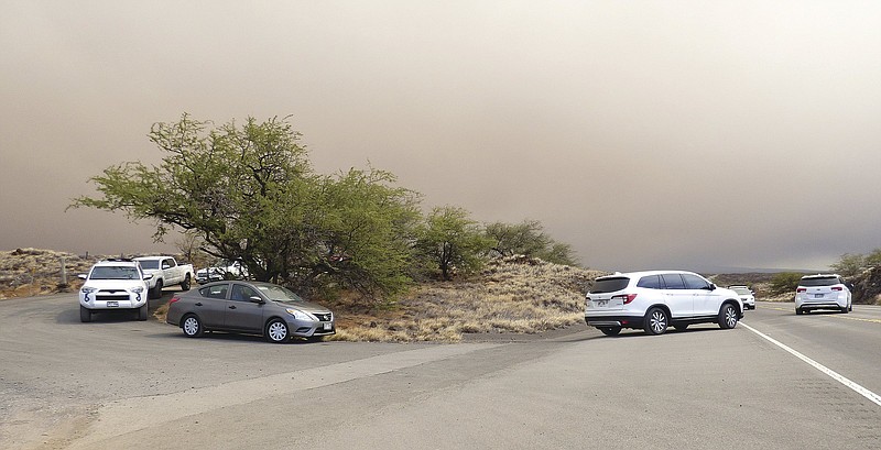 Vehicles turn onto Queen Kaahumanu Highway from an emergency access route opened after residents and visitors lodging in the Waikoloa Village area of Hawaii were ordered to evacuate as a wildfire threatened the South Kohala town Sunday, Aug. 1, 2021. (Chelsea Jensen/West Hawaii Today via AP)