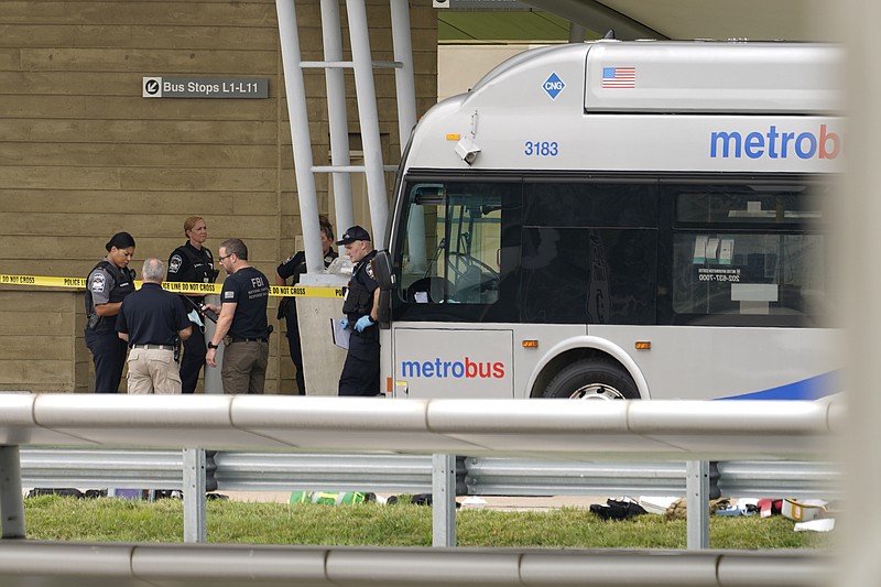 Police are looking at a scene and items are seen on the ground near a Metrobus outside the Pentagon Metro area, Tuesday, Aug. 3, 2021 at the Pentagon in Washington. A Pentagon police officer died after being stabbed Tuesday during a burst of violence at a transit station outside the building. That's according to law enforcement officials. The Pentagon officer was stabbed and later died, according to officials who were not authorized to discuss the matter and spoke to The Associated Press on condition of anonymity.  (AP Photo/Andrew Harnik)