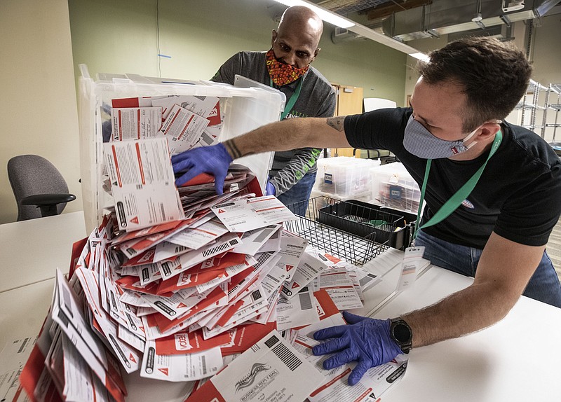 Dondre Marshall, left, and Taylor Whitmire dump ballots cast in Seattle’s mayoral primary for sorting at the King County Elections Headquarters in Renton, Wash., on Election Day, Tuesday. - Steve Ringman/The Seattle Times via AP
