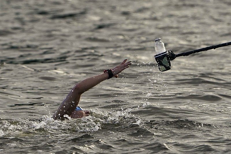 Souad Nefissa Cherouati, of Algeria, grabs a drink at a feeding station during the women's marathon swimming at the 2020 Summer Olympics Wednesday in Tokyo. - Photo by Jae C. Hong of The Associated Press