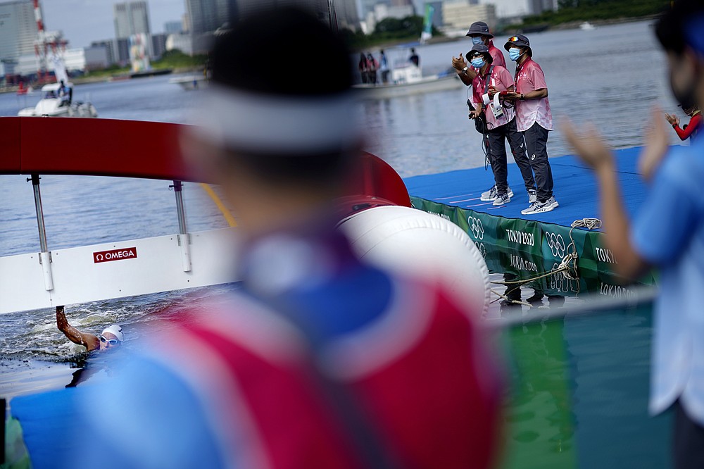 Officials applaud as Souad Nefissa Cherouati, of Algeria, finishes last in the women's marathon swimming event at the 2020 Summer Olympics, Wednesday, Aug. 4, 2021, in Tokyo. (AP Photo/David Goldman)
