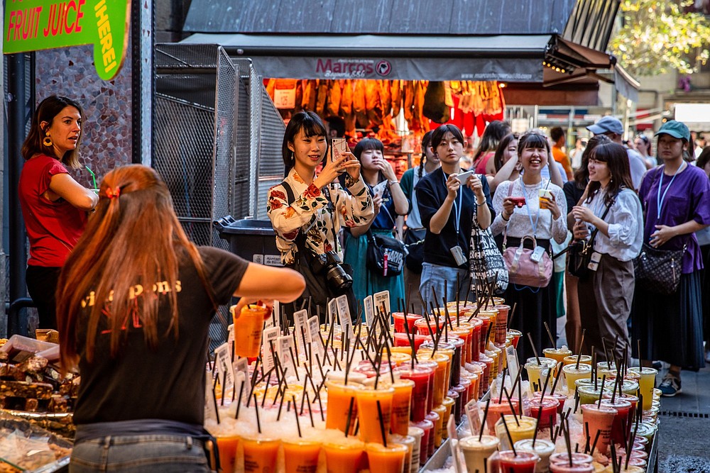 Tourists take smartphone photographs at La Boqueria food market in Barcelona, Spain, in 2019. The market closed during the pandemic but has reopened. (Bloomberg/Angel Garcia)