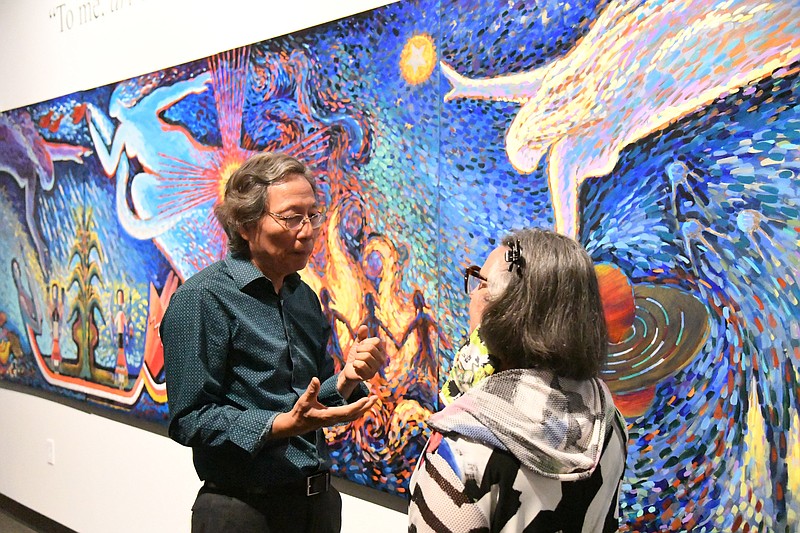 Longhua Xu, left, discusses his artwork with a patron at the opening reception of “Crayons to Canvas” at Mid-America Science Museum in May. - File photo by The Sentinel-Record