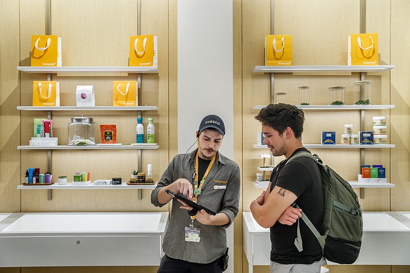 Paul Melone, left, helps customer Brandon Nguyen, 27, at the Sunnyside dispensary in Chicago's River North neighborhood on July 28, 2021. The dispensary is the closest marijuana shop to the Lollapalooza music festival. (Armando L. Sanchez/Chicago Tribune via AP)