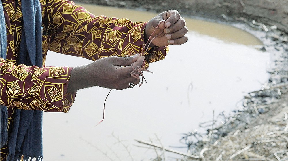 The hands of Garey Youhanis, an Ethiopian from Tigray who is living in Sudan and was one of the men who found dead bodies in the Setir River demonstrates with a red cord how the bodies had been tied at Wad el Hilu, Sudan on Wednesday, Aug. 4 2021. Dozens of bodies have been found floating down the Setit River, known in Ethiopia as Tekeze River, in southwestern Sudan in the past week. (AP Photo/Mohaned Awad)