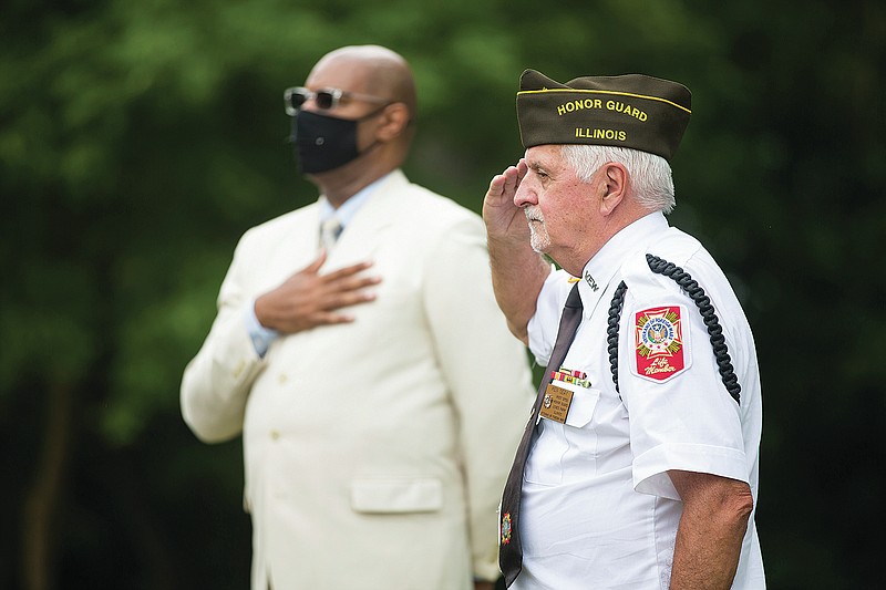 Ken Seay, right, of the Color Guard of VFW Post 9759 in Loves Park, salutes the American flag during a memorial service at River Bluff Nursing Home, Friday, July 30, 2021, in Rockford, Ill.   Between 1854 and 1954 more than 600 mostly unknown and forgotten men, women, and children were buried in unmarked graves behind the grounds of the current nursing home. (Scott P. Yates /Rockford Register Star via AP)