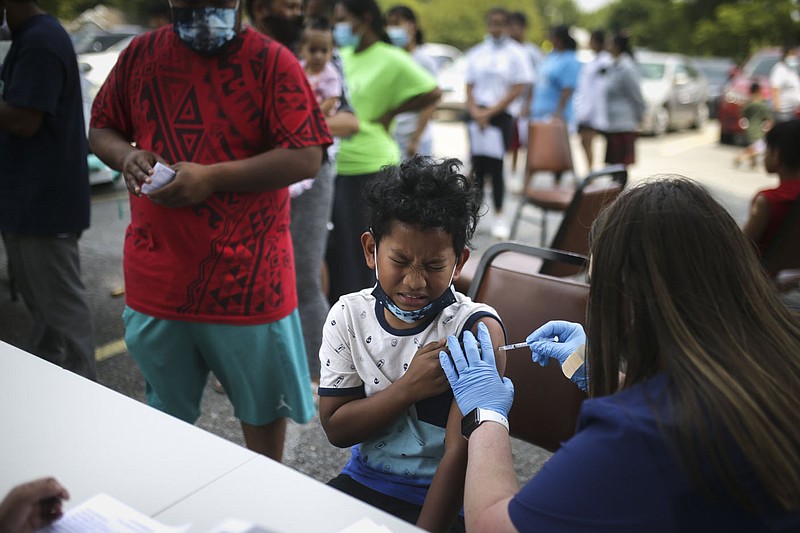 Pharmacist Victoria Hennessey, owner of Community Pharmacy, (right) administers a covid-19 vaccine to Linson Kablo, 12, Friday, August 6, 2021 at a pop-up vaccination clinic at the First United Methodist Church in Springdale. Community Pharmacy of Springdale administered vaccines to the Marshallese community. Check out nwaonline.com/210807Daily/ for today's photo gallery. 
(NWA Democrat-Gazette/Charlie Kaijo)