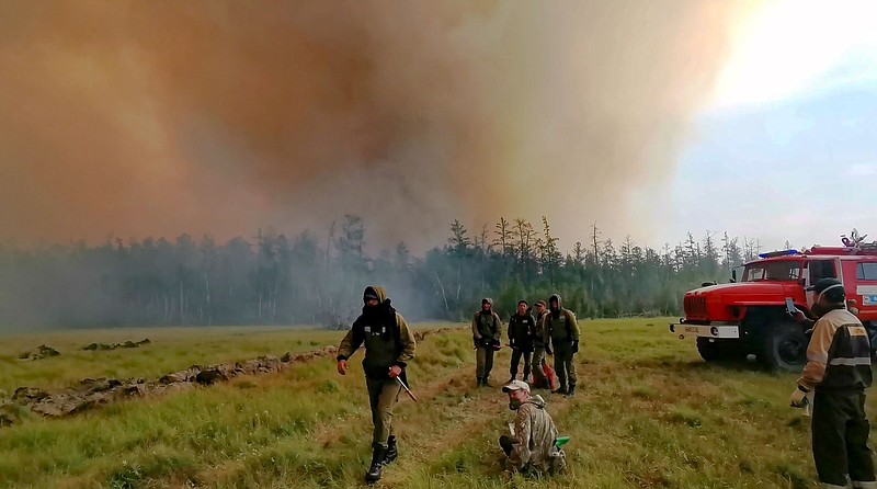 Firefighters gather as they work at the scene of forest fire at Gorny Ulus area west of Yakutsk, in Russia, Saturday, Aug. 7, 2021. Wildfires in Russia's vast Siberia region endangered several villages Saturday and prompted authorities to evacuate residents of some areas. In northeastern Siberia, 93 active forest fires burned across 1.1 million hectares (2.8 million acres) of Sakha-Yakutia, officials said, making it the worst affected region of Russia. (AP Photo/Ivan Nikiforov)