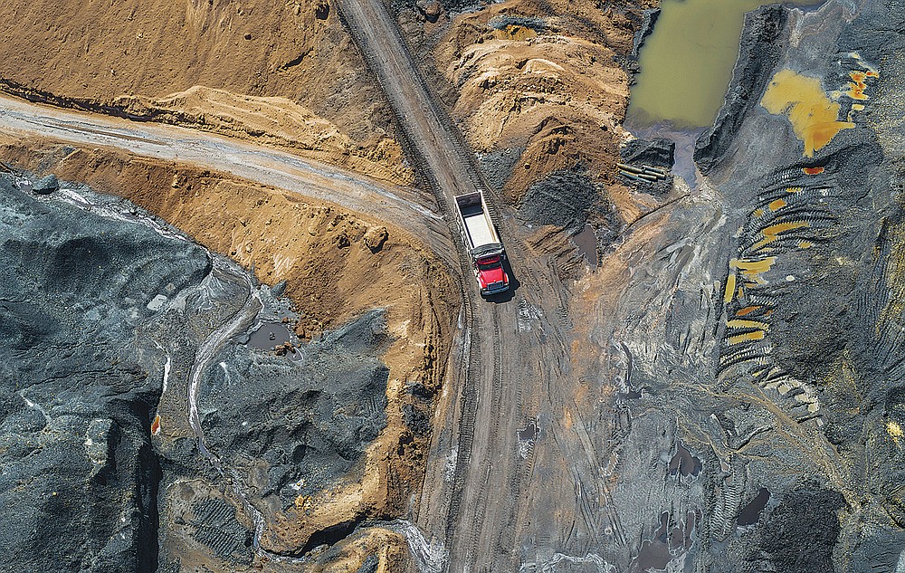 A truck drives to pickup a load of material at a Russellton coal waste pile on Friday, July 23, 2021, in Russellton, Pa. The pile is being trucked to be used at the Scrubgrass Power plant in Venango County and later returned in the form of ash. (Andrew Rush/Pittsburgh Post-Gazette via AP)