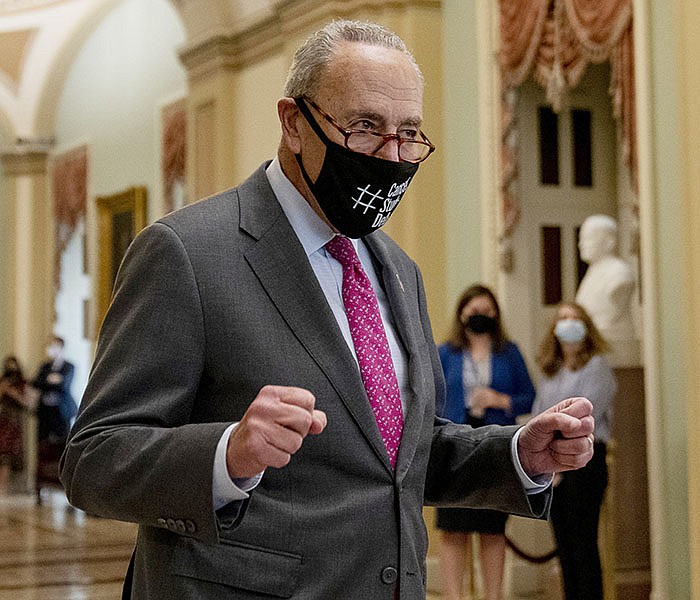 Senate Majority Leader Charles Schumer clenches his fists in triumph Tuesday as he walks off the Senate floor after approval of a $1 trillion measure that would be the largest infusion of federal investment into infrastructure projects in more than a decade.
(AP/Andrew Harnik)