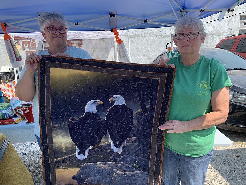 SALLY CARROLL/SPECIAL TO MCDONALD COUNTY PRESS Tammy Sweetwood, left, and Teresa Tate, right, show off a hand-crafted quilt at Mountain Happenings at Sims Corner. The two showcased quilts from Tate's parents' shop, which is located in Stella.