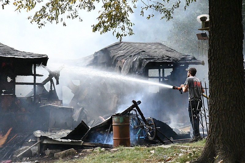 A Piney Fire Department firefighter blasts water onto the smoldering remains of a trailer home at 181 Skeet Drive that was destroyed by fire Tuesday evening. - Photo by Tanner Newton of The Sentinel-Record