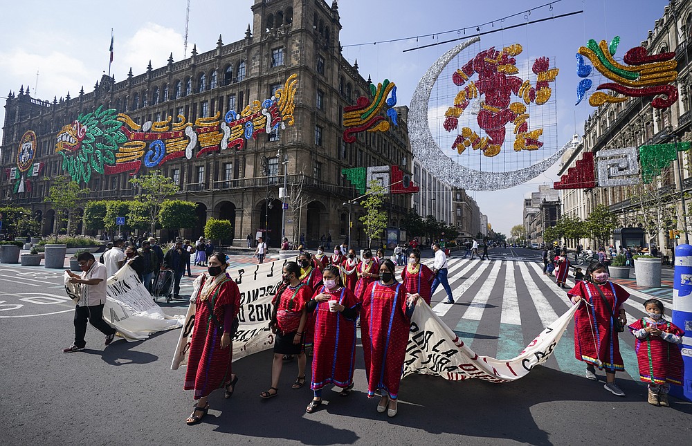 Triquis Indigenous people, originally of Oaxaca state but who live in Mexico City, protest under an image pf the Pre-Columbian moon goddess Coyolxauhqui, to be allowed to sell their wares near Mexico City´s main square the Zocalo, Monday, Aug. 9, 2021. Mexico City is preparing for the 500 anniversary of the fall of the Aztec capital of Tenochtitlan, today´s Mexico City, on Aug. 13, 2021. (AP Photo/Eduardo Verdugo)
