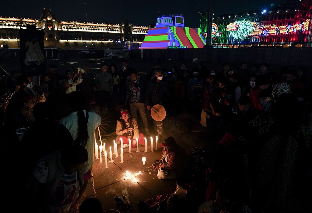 Mexican dancers light a candle during a ceremony to commemorate the 500th anniversary of the fall of the Aztec empire capital of Tenochtitlan, known today as Mexico City, at Mexico City's main square the Zocalo, Friday, Aug. 13, 2021. (AP Photo/Eduardo Verdugo)