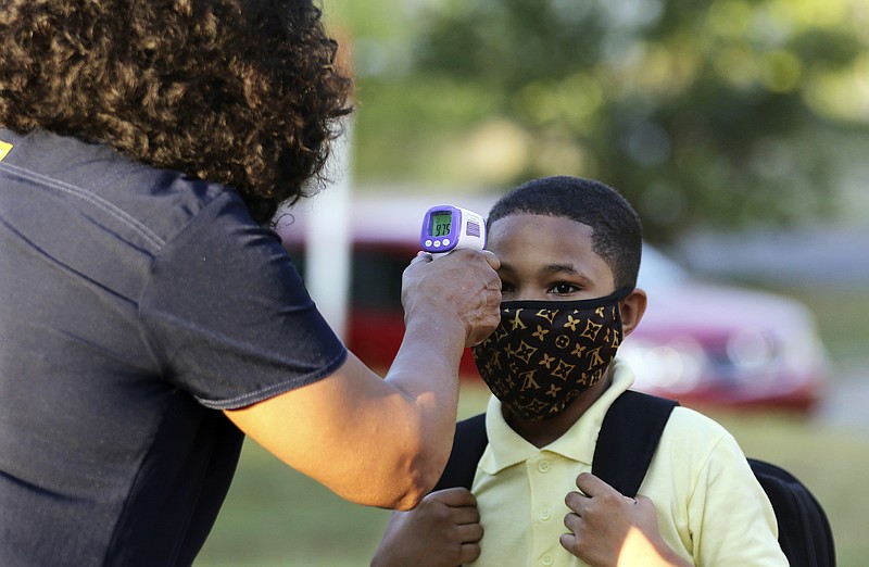 In this Monday, Aug. 24, 2020, file photo, fifth-grader Marcques Haley, gets his temperature checked by school nurse Rachel White before entering Stephens Elementary School in Little Rock, Ark. Most Arkansas public school students will be required to wear masks when 2001 classes begin in mid-August 2021, following moves by dozens of districts in response to a judge blocking the state's mask mandate ban. (Tommy Metthe/The Arkansas Democrat-Gazette via AP, File)