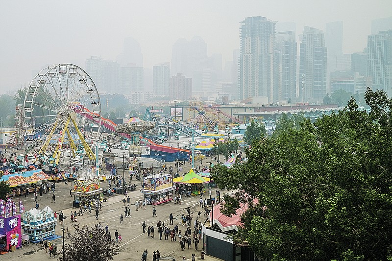 FILE - In this Sunday, July 18, 2021 file photo, smoke from wildfires is carried by winds, obscuring the view for visitors to the Calgary Stampede in Calgary, Alberta. On Friday, Aug. 13, 2021, The Associated Press reported on stories circulating online incorrectly asserting the Canadian province of Alberta lifted all COVID-19 restrictions after health officials couldn&#x2019;t provide evidence in court that the virus exists. Alberta relaxed its restrictions because the province hit predetermined vaccination goals, not because of a court case. (Jeff McIntosh/The Canadian Press via AP, File)