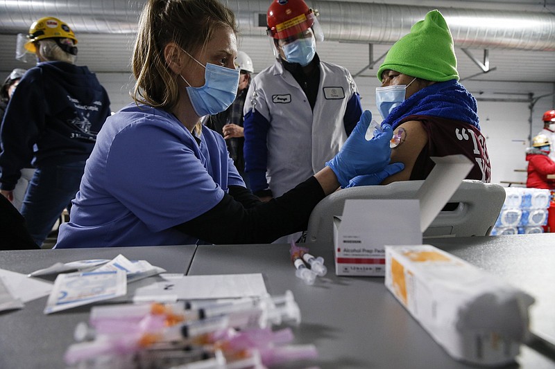 A Tyson Foods team member receives a COVID-19 vaccine from health officials at the Joslin, Ill., facility on Friday, Feb. 19, 2021. A growing number of companies and labor unions are directly securing coronavirus vaccines for their workers. Tyson also has expanded its on-site event to include eligible family members of employees. (John Konstantaras/AP Images for Tyson Foods)