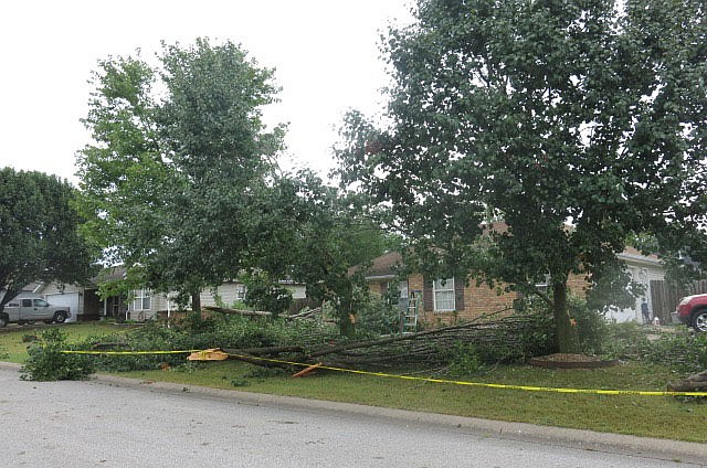 Westside Eagle Observer/SUSAN HOLLAND
Yellow warning tape encircles the yard at the home of Josh and Tabby Crane on the corner of Dallas Street S.E. and Westfield Street in Gravette. A sudden rain and windstorm blew up late Friday afternoon and snapped a whole row of trees in the Crane's front yard. The Crane home is just north of Pop Allum Park.