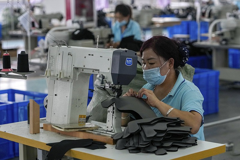 Workers wearing face masks to help curb the spread of the coronavirus sew layers for ice-skating shoes at a manufacturing factory in the ice and snow sports equipment industry park in Zhangjiakou in northwestern China's Hebei province on July 15, 2021. China's retail sales and industrial production growth weakened in July as floods and COVID-19 outbreaks in parts of China disrupted the consumption and supply chain, a government spokesperson said on Monday, Aug. 16, 2021.