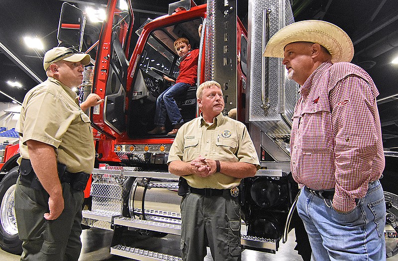 Agent Justin Smith, left, and Assistant Chief Russ Lancaster, center, both with the State Department of Agriculture?s law enforcement team, talk with Keith Stokes, an agriculture project manager for the office of Senator Tom Cotton, while he attends the Southwest Forest Expo with his grandson Colt Stokes, 7, on Friday, Aug. 13, 2021 in Hot Springs.
(Arkansas Democrat-Gazette/Staci Vandagriff)