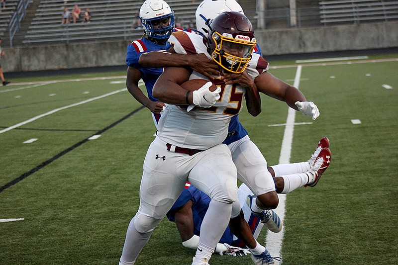 Lake Hamilton senior running back Tevin Hughes (25) drags Arkadelphia sophomore Lamont Jones in a drive to the end zone in the second half of Monday&#x2019;s scrimmage at Badger Stadium. - Photo by James Leigh of The Sentinel-Record