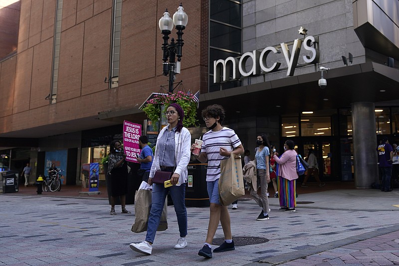 FILE - In this July 14, 2021 file photo, pedestrians pass the Macy's store in the Downtown Crossing shopping area, in Boston.   Americans cut back on their spending last month as a surge in COVID-19 cases kept people away from stores. Retail sales fell a seasonal adjusted 1.1% in July from the month before, the U.S. Commerce Department said Tuesday, Aug. 17.   (AP Photo/Charles Krupa, File)