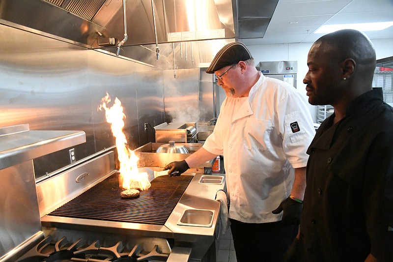 Michael Dampier, Ohio Club kitchen general manager, left, and Adrian Poland, senior head cook, prepare hamburgers in the Ohio Club’s new kitchen, which reopens today. - Photo by Tanner Newton of The Sentinel-Record