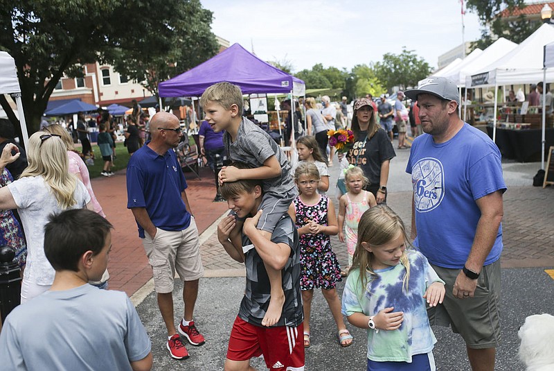 Stephen Schafer, 12, of Bentonville (center left) carries Gideon Pillmore, 5, on his shoulders, Saturday, August 21, 2021 during the Farmer's Market at the downtown square in Bentonville. Northwest Arkansas grew in population in the latest U.S. Census. Check out nwaonline.com/210822Daily/ for today's photo gallery. 
(NWA Democrat-Gazette/Charlie Kaijo)